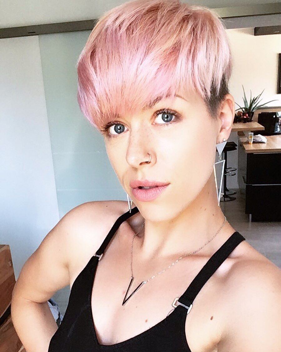 femme au long visage avec une coiffure rose coupée en lutin