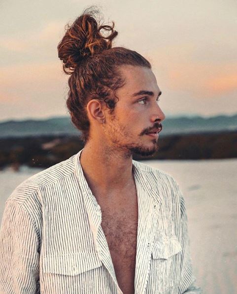 Homme aux cheveux bouclés dans un chignon d'homme 