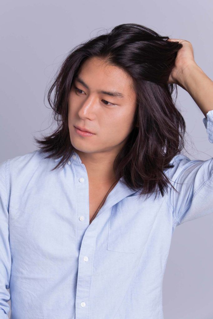 Un homme asiatique, un petit pain : Modèle masculin asiatique dont les cheveux à la longueur des épaules touchent ses cheveux