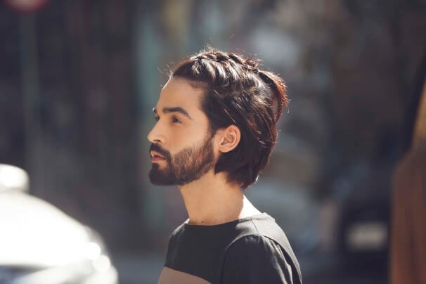 Homme aux cheveux mi-longs tressés, brun foncé et raides