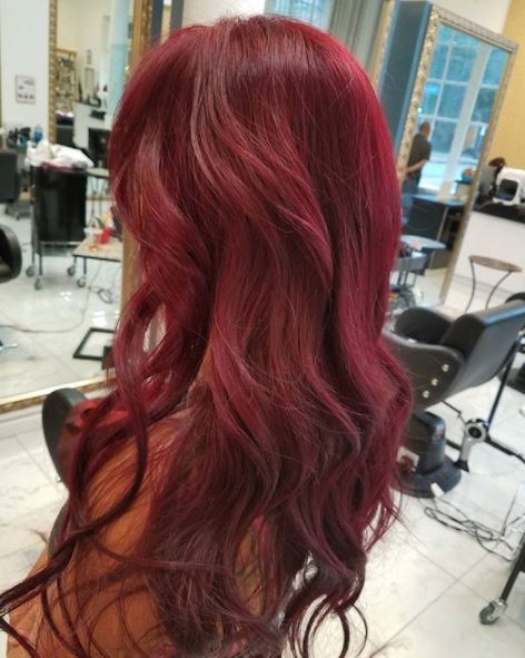 femme avec de longs cheveux ondulés d'un rouge profond