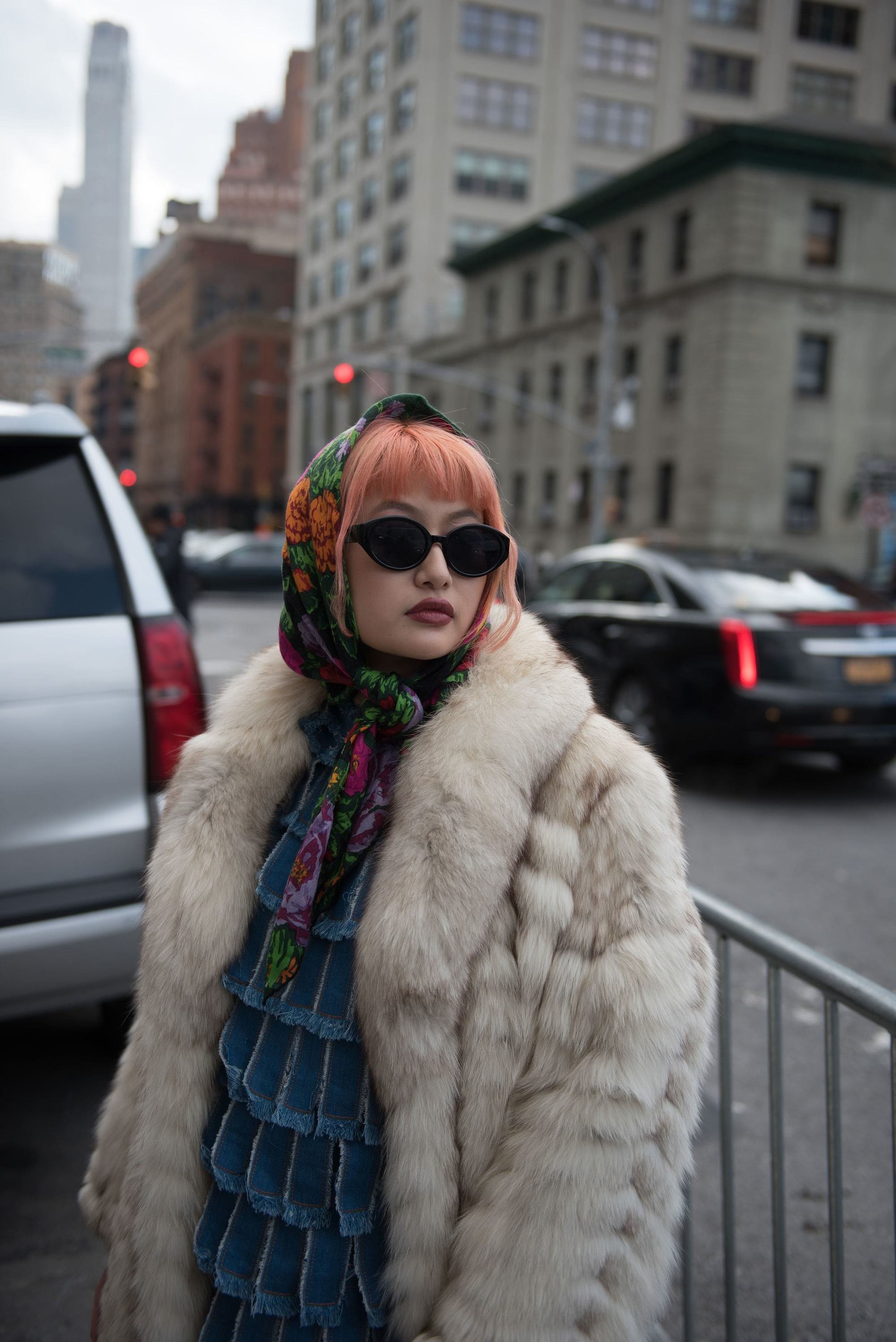 Femme aux cheveux roses avec une frange attachée dans un foulard à motifs.