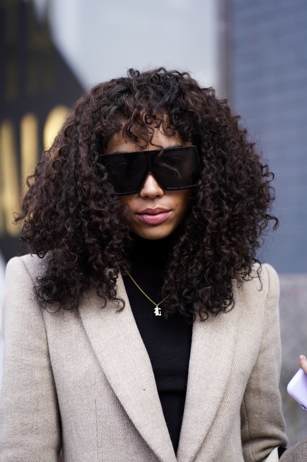 Femme avec des cheveux naturels bruns foncés et bouclés avec une frange.