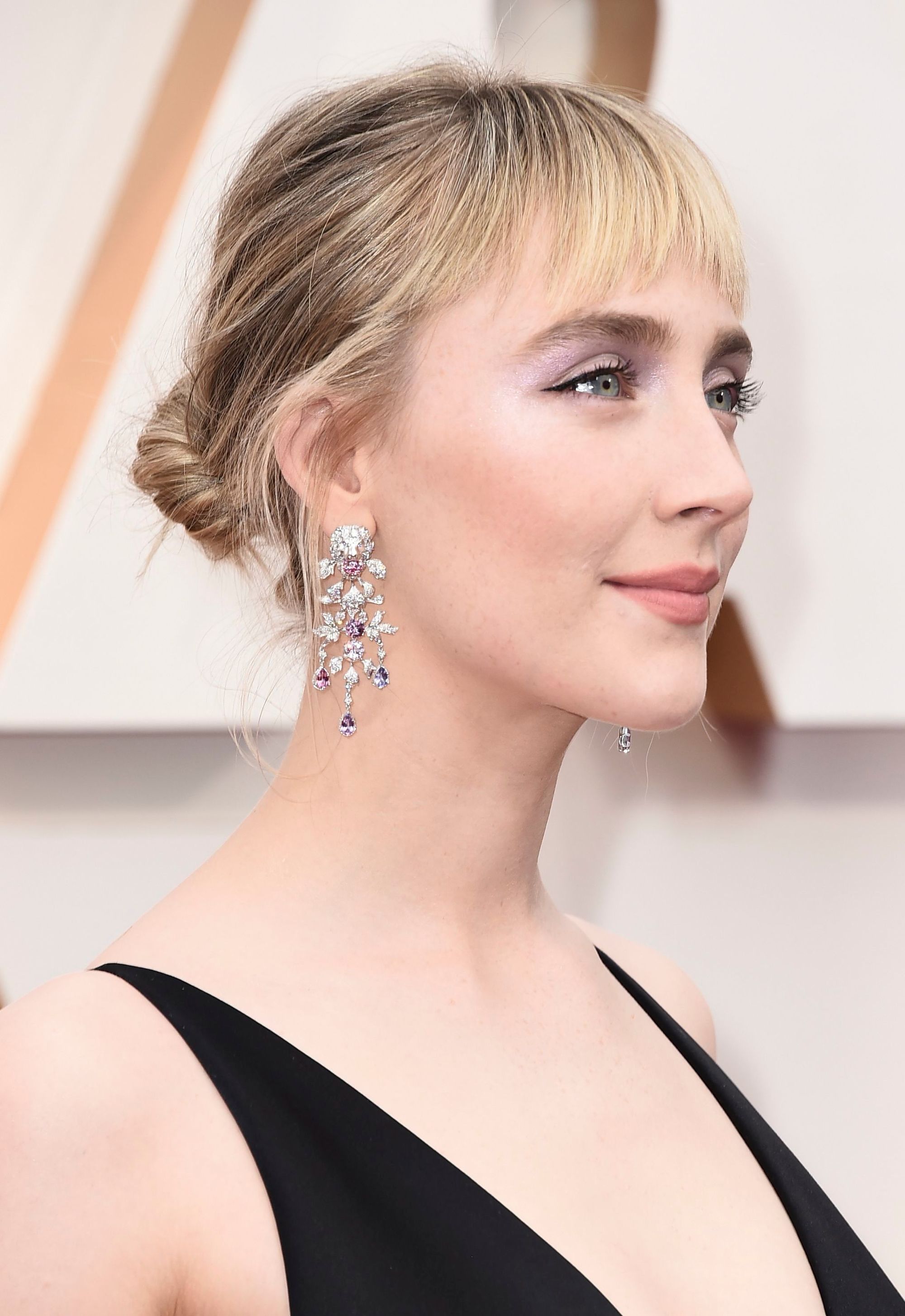 Saoirse Ronan avec des cheveux blonds dans un chignon haut bas avec une frange lors des Oscars 2020.
