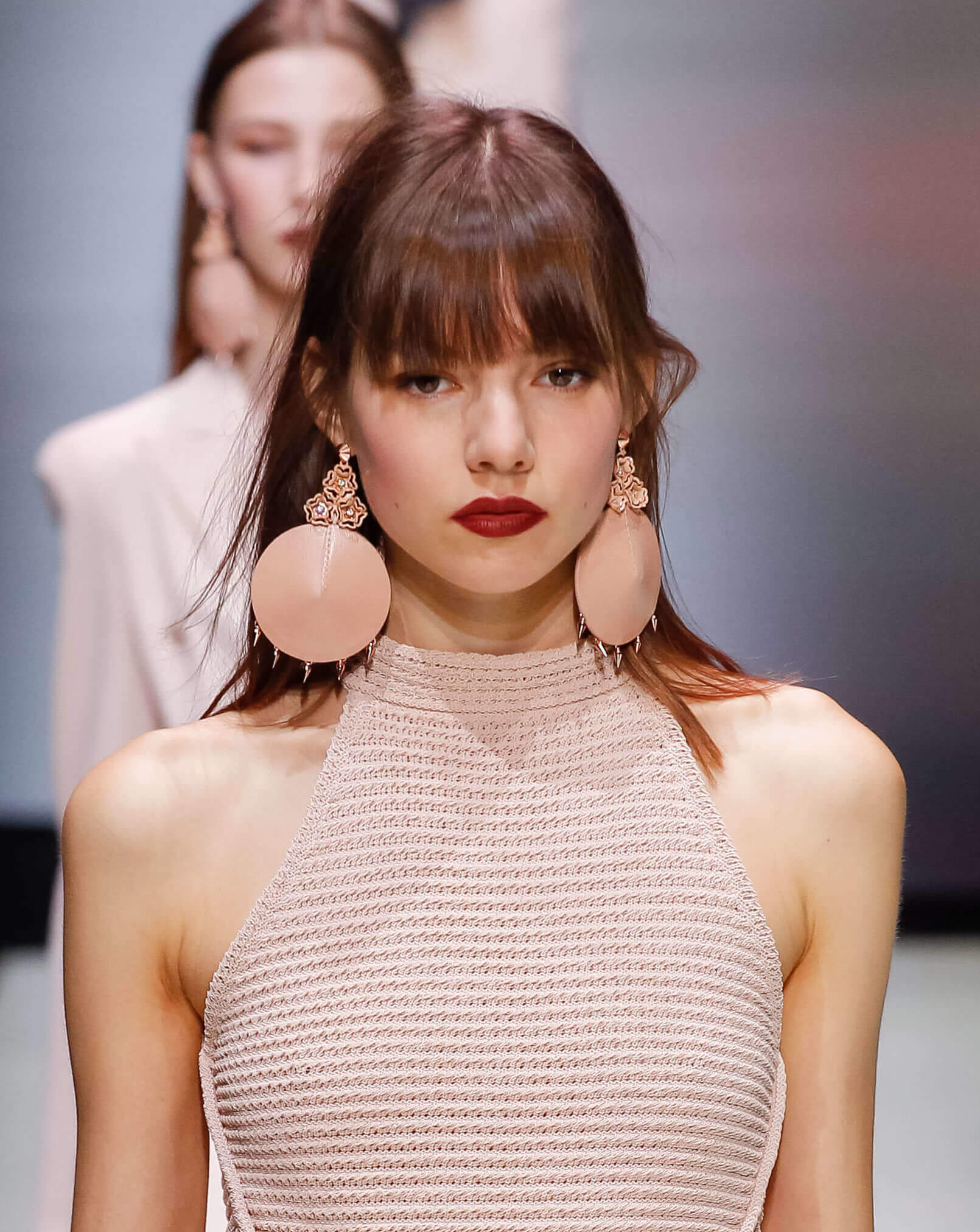 femme sur la piste avec une coiffure à frange longue portant une tenue rose pastel