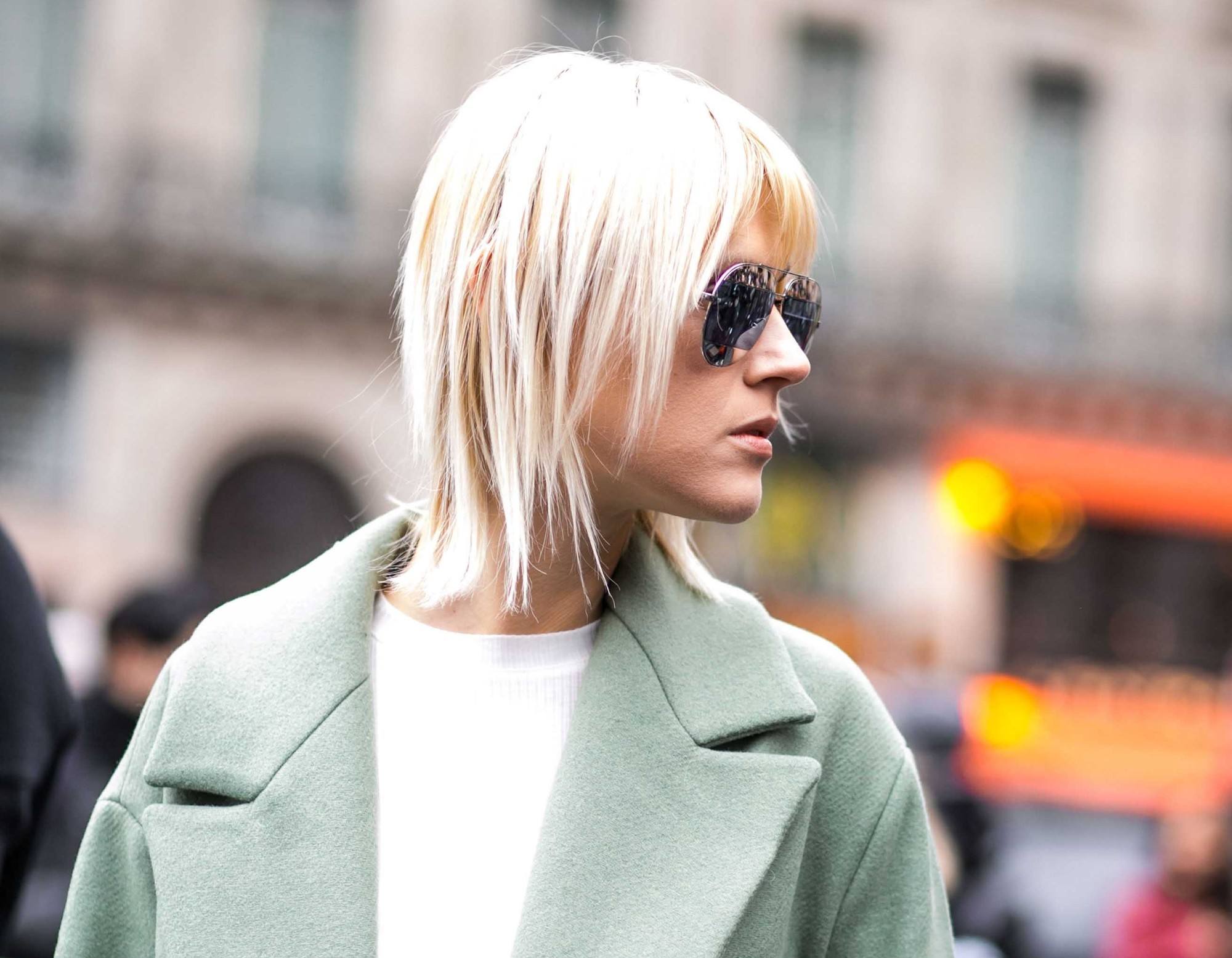 Femme blonde avec des cheveux courts et une coupe de cheveux à frange regardant vers sa droite.