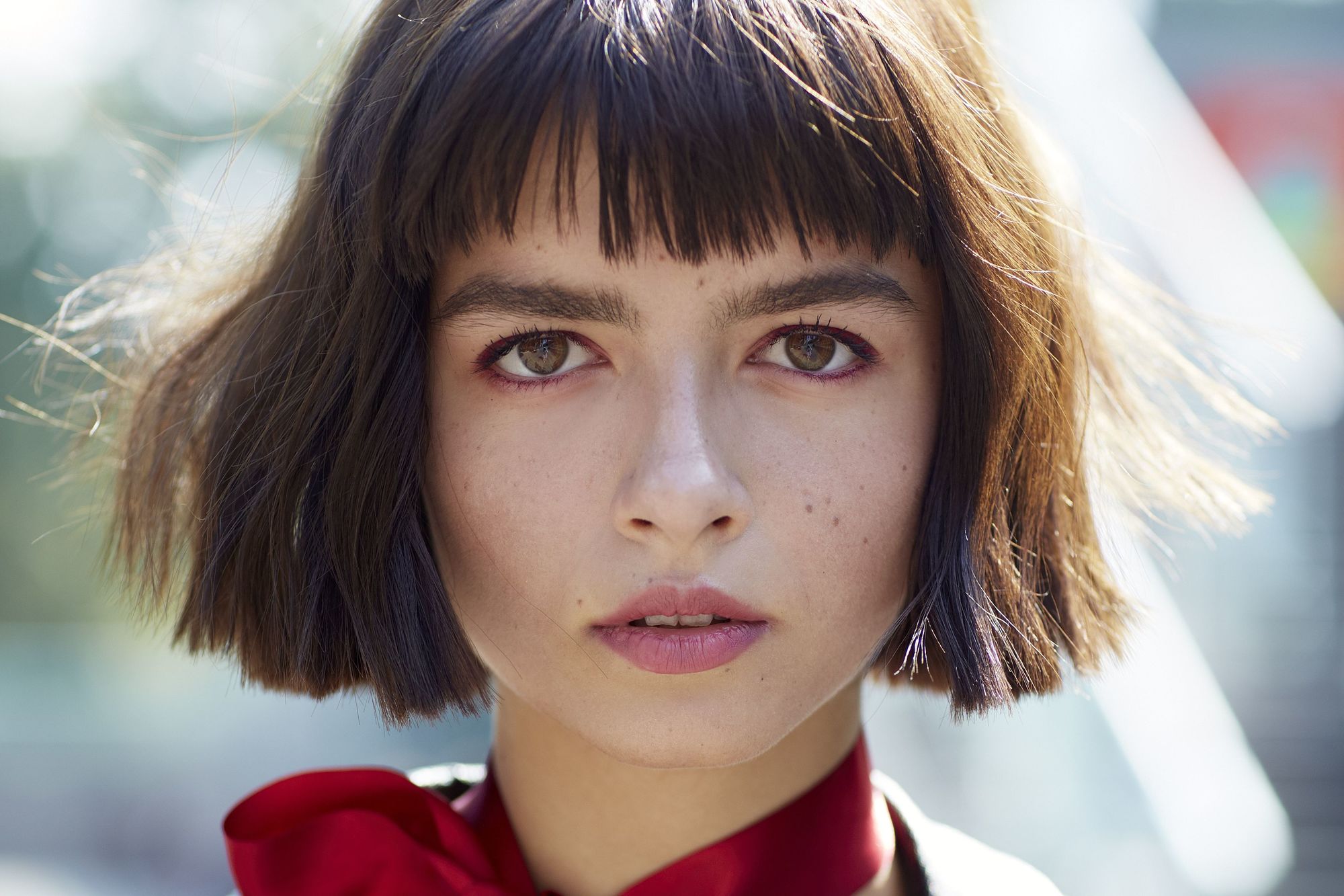 Cheveux courts avec frange : gros plan d'un mannequin de style urbain aux cheveux courts avec frange, portant un foulard rouge.