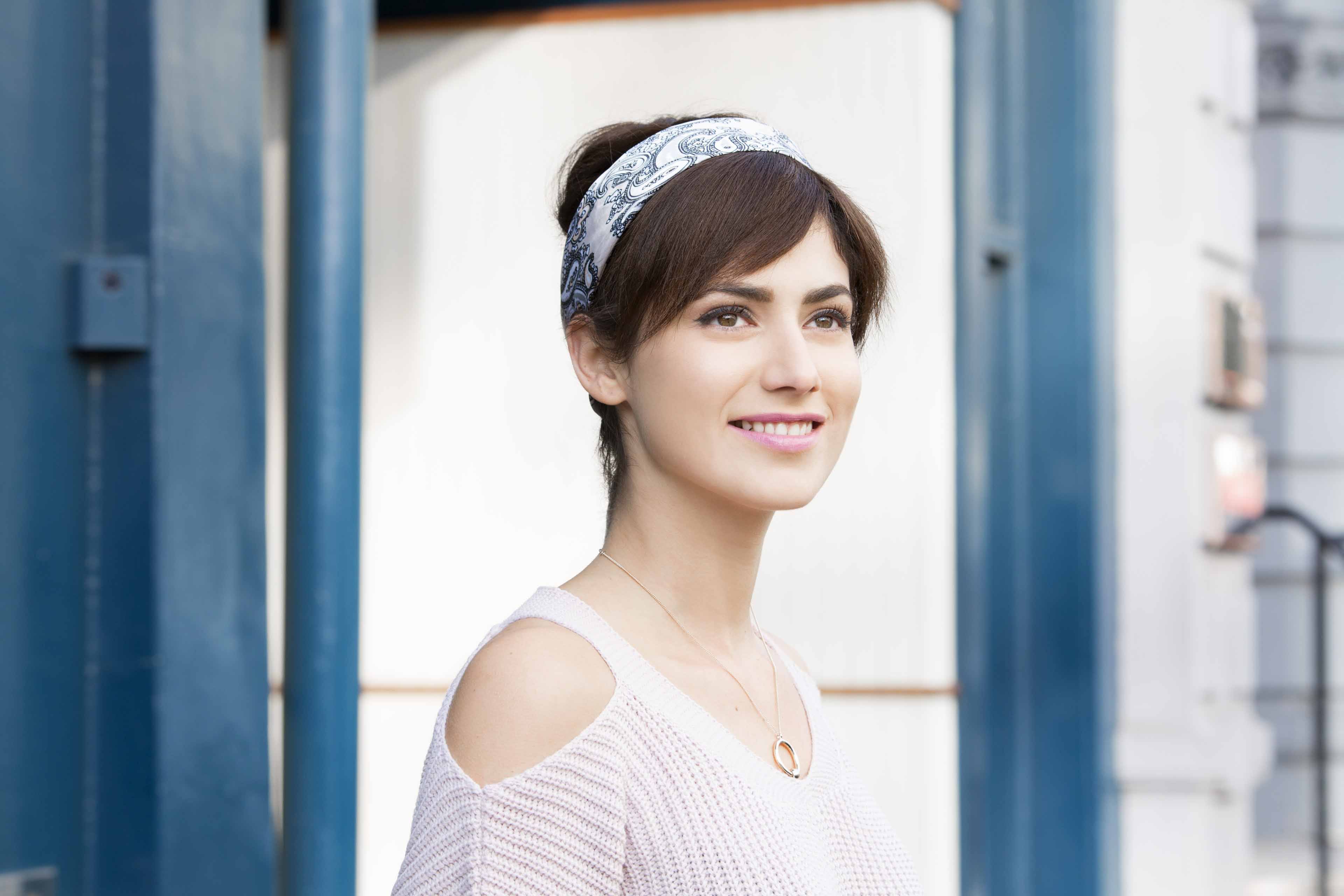 une fille avec des cheveux en fausse frange souriant à l'extérieur