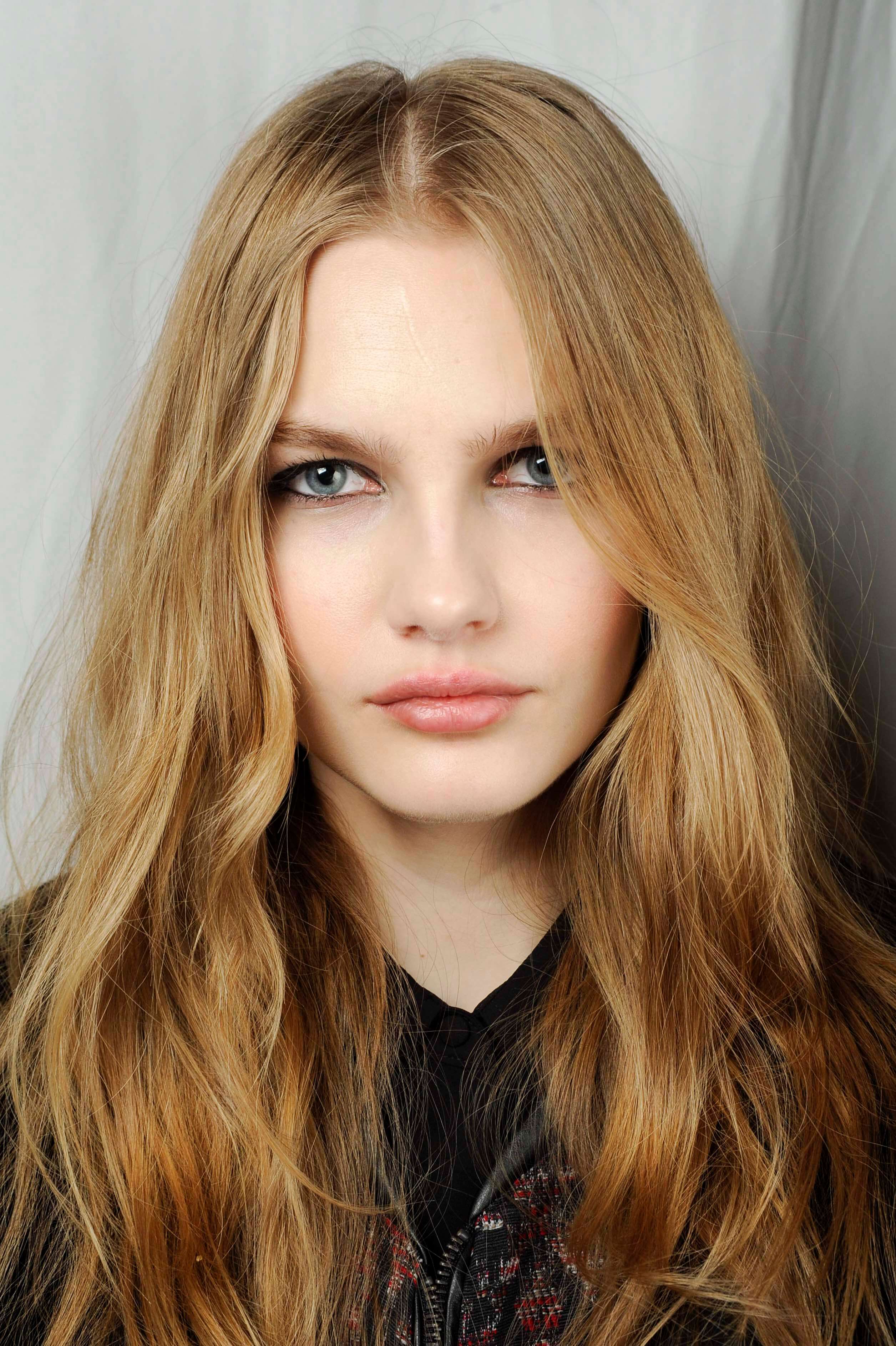 Nuances de cheveux blonds : Femme aux longs cheveux blonds chauds ondulés, portant un haut noir.