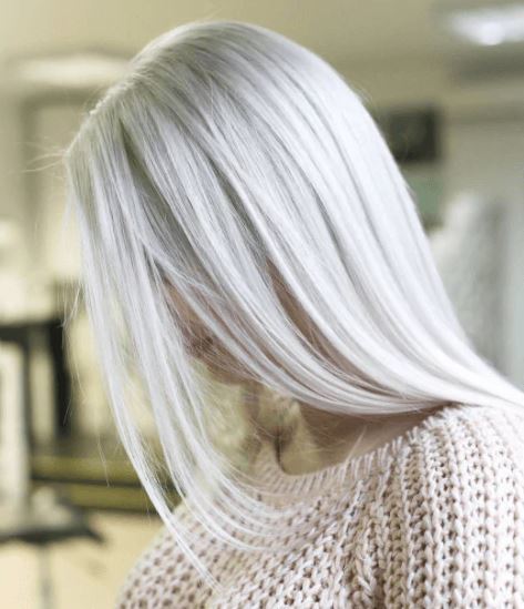 Nuances de cheveux blonds : Femme aux cheveux longs et raides d'un blond glacé, portant un pull en tricot beige.