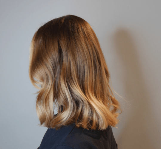 vue de côté d'une femme aux cheveux longs aux épaules avec des vagues et différentes nuances de blond