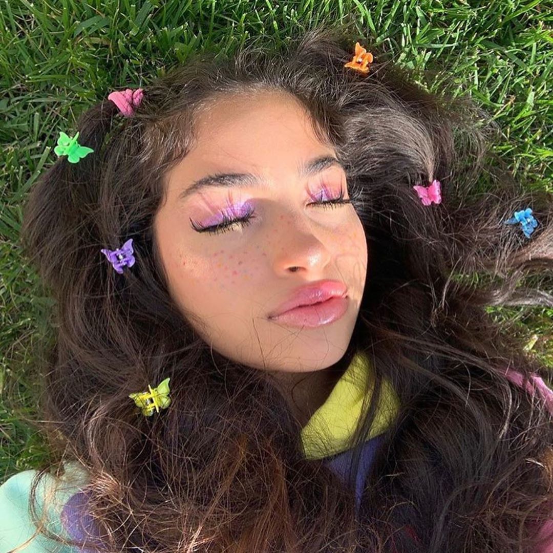 Fille aux longs cheveux bruns couverts de pinces à cheveux en forme de papillon 