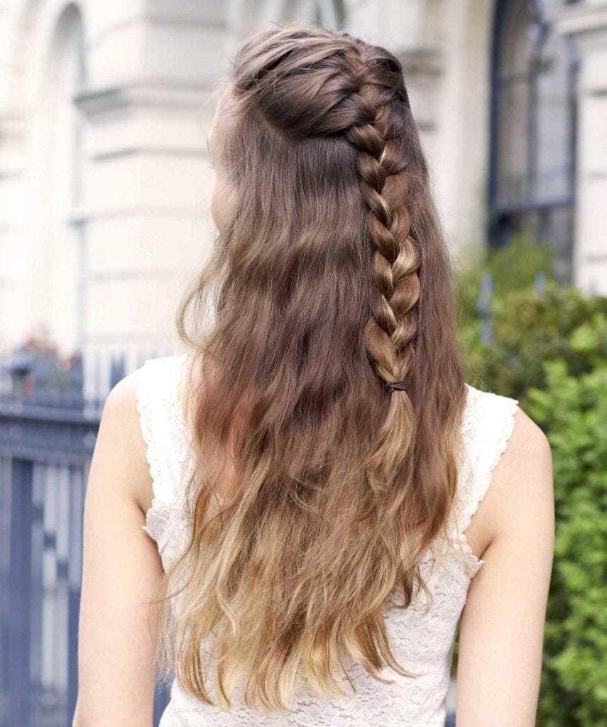 Des tresses faciles pour les cheveux longs : Vue de dos d'une femme aux cheveux longs ondulés de couleur brune ombre dans une coiffure tressée à mi-hauteur