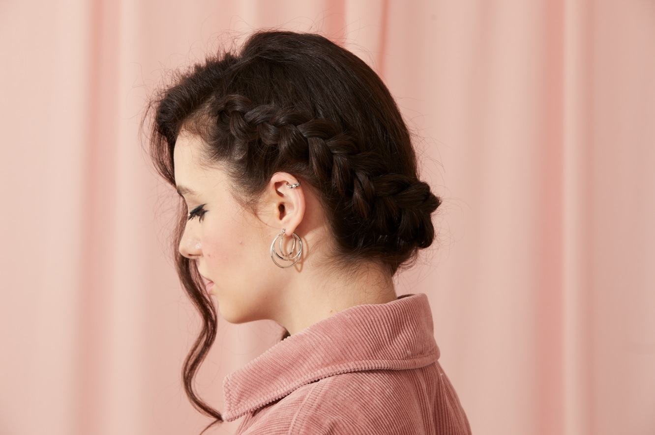 Femme aux cheveux brun chocolat, avec une tresse de couronne hollandaise sur le côté et une vrille de cheveux bouclés