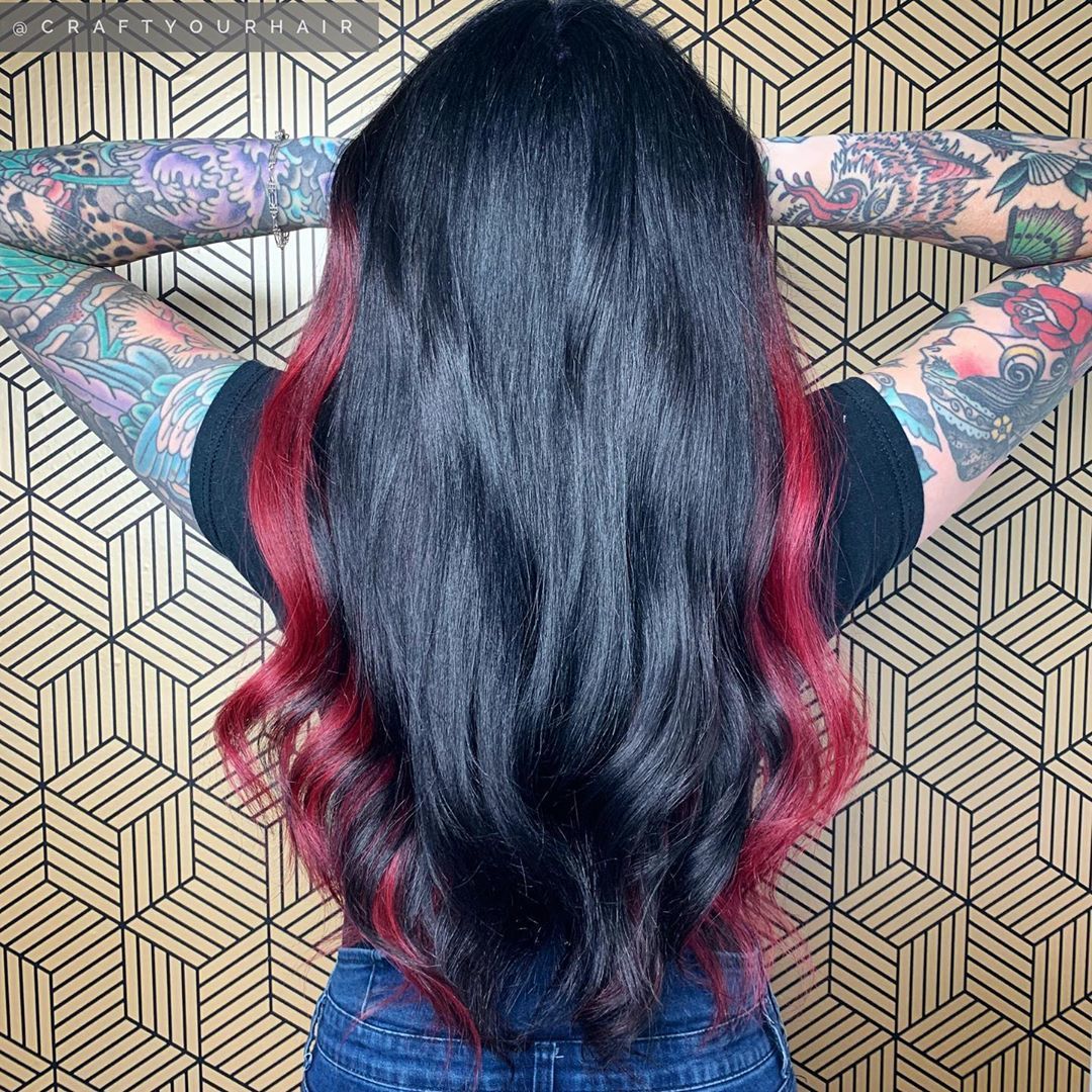 Femme aux longs cheveux noirs avec des reflets rouges sur les côtés