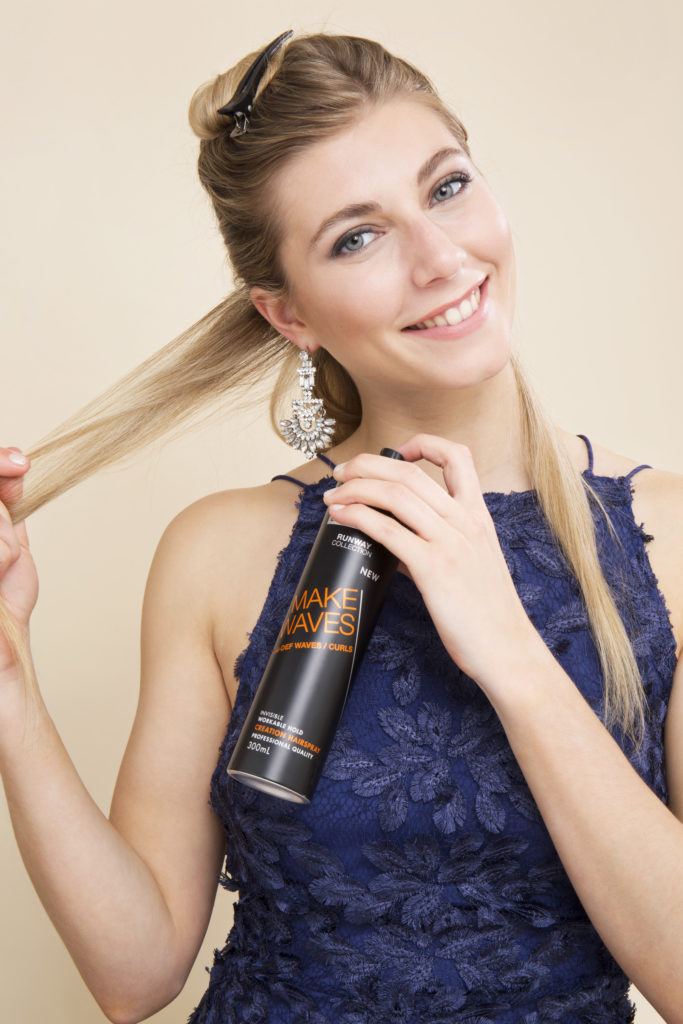 une belle femme blonde vaporisant ses longs cheveux