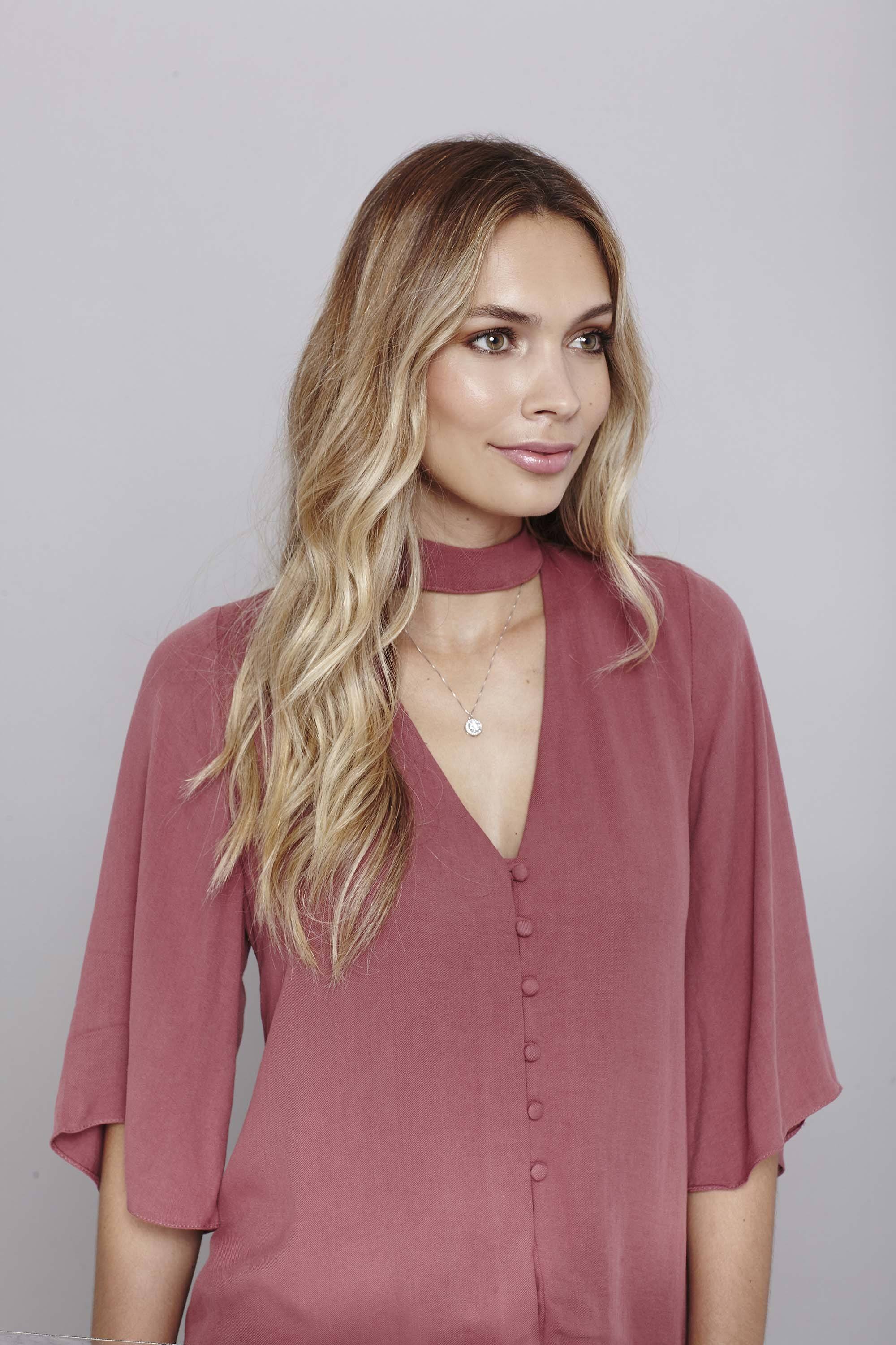 modèle avec des boucles ondulées lâches portant une chemise rose - tutoriel sur la façon de friser les cheveux avec un fer plat