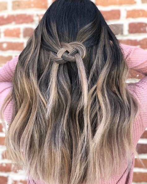 Femme aux cheveux bruns de balayage dans une tresse de nœud celtique