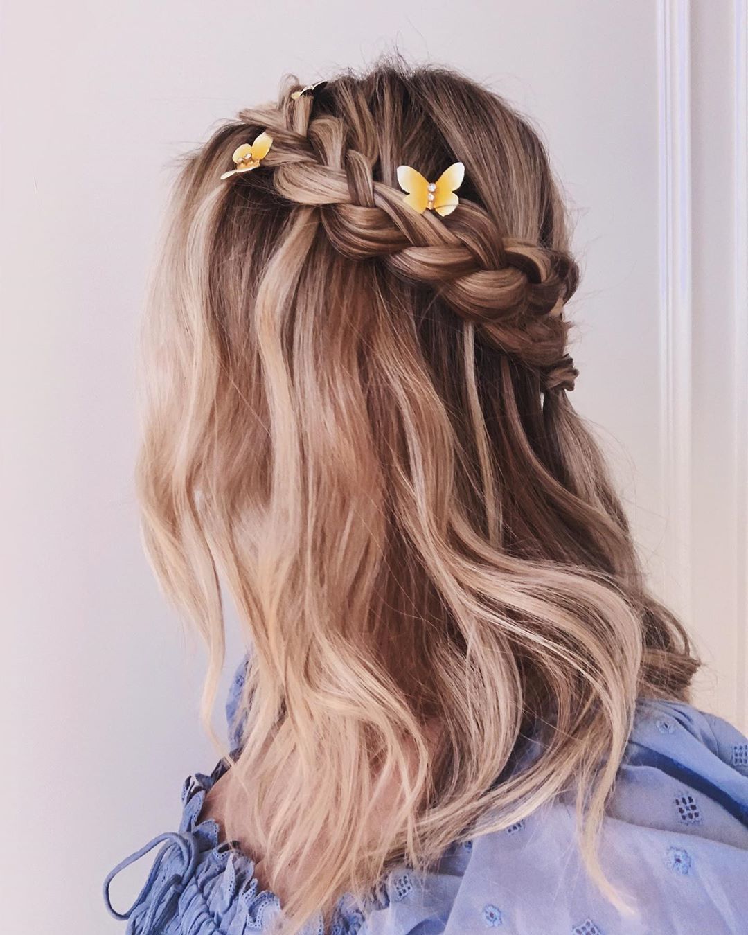 Femme aux cheveux blonds beiges dans une tresse en demi-lune avec des pinces papillon