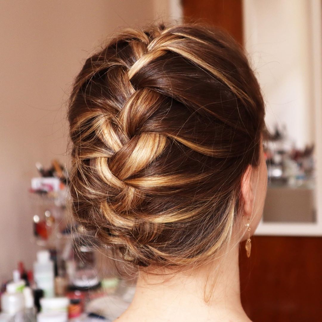 Femme aux cheveux bruns soulignés dans un updo français tressé