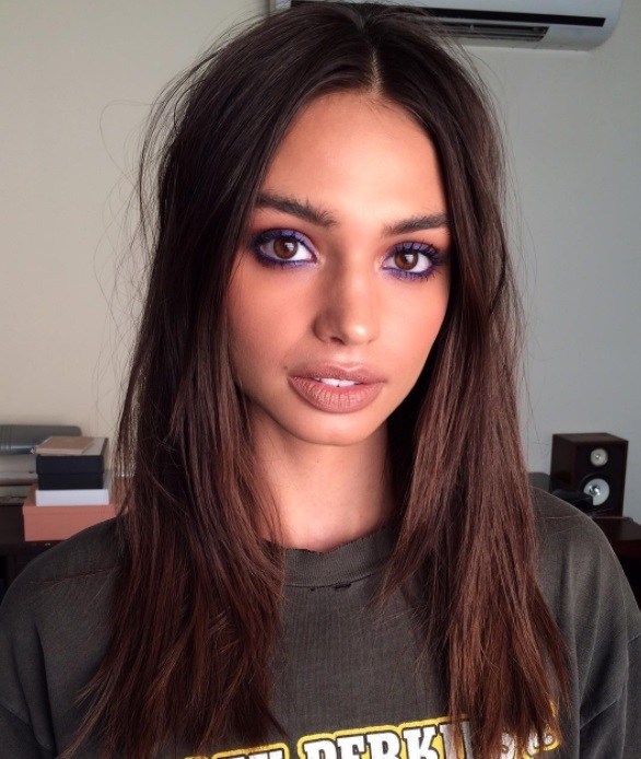 plan de face d'un mannequin aux cheveux châtain foncé avec une pose minimale de maquillage