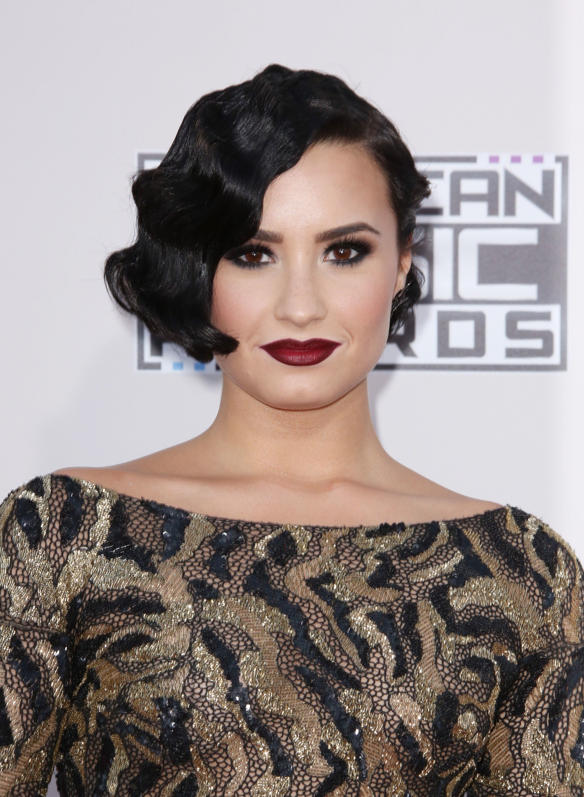 Cheveux courts vintage : Gros plan de Demi Lovato avec des cheveux courts brun foncé coiffés en un doigt ondulé sur le tapis rouge