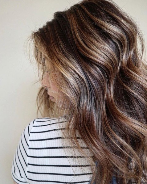 Femme aux cheveux bruns ondulés en balayage