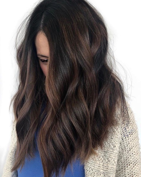 Femme aux cheveux mi-longs, ondulés, brun foncé, en balayage