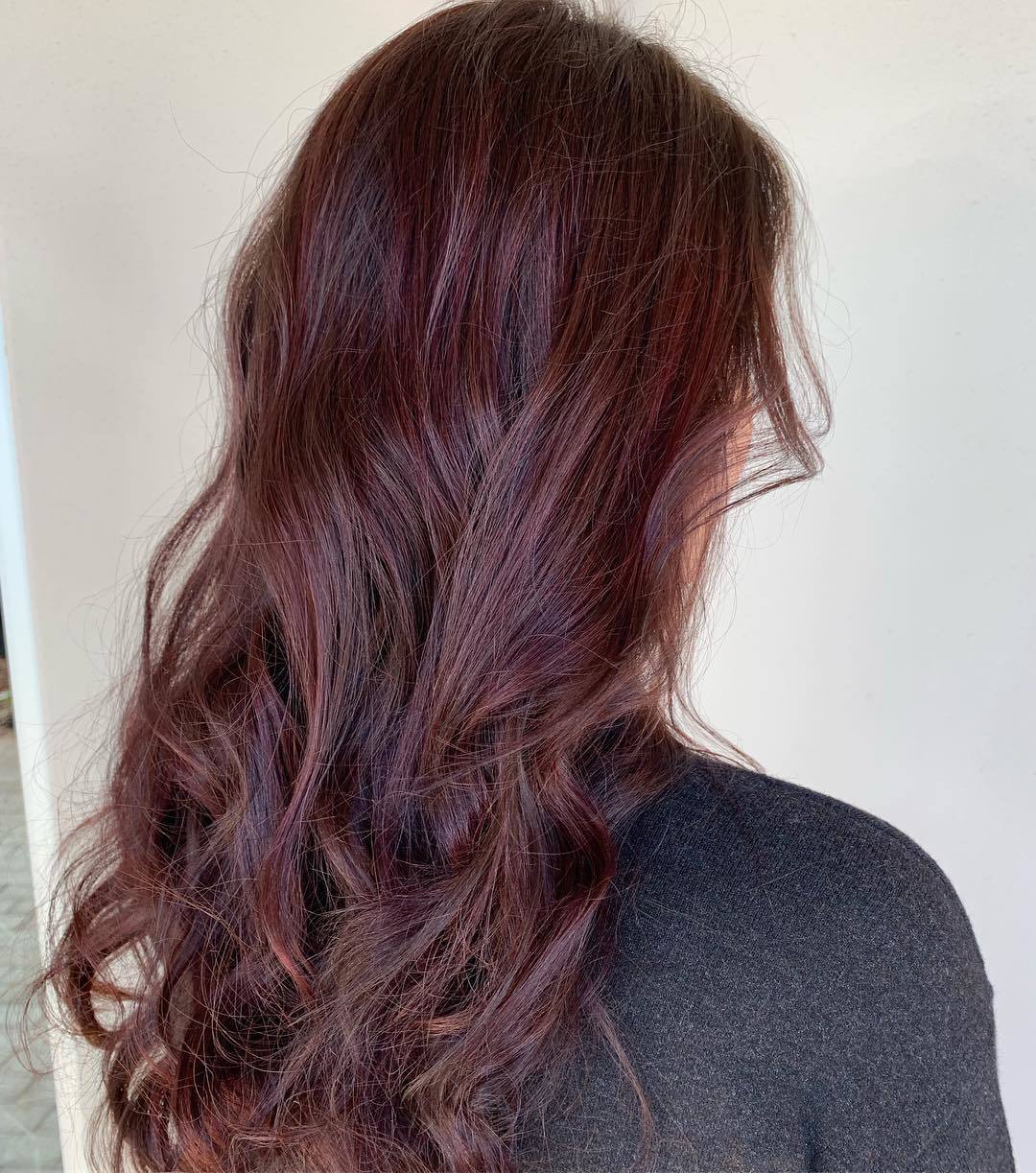 Femme avec de longs cheveux bouclés acajou rouge balayage