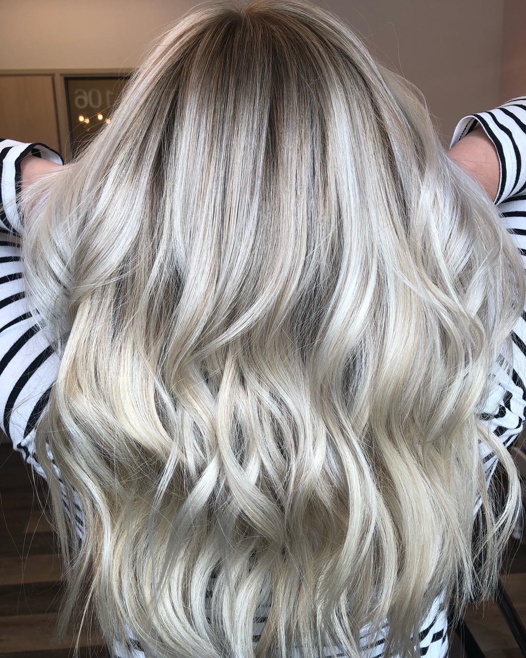 Femme aux longs cheveux ondulés et blonds perlés en balayage