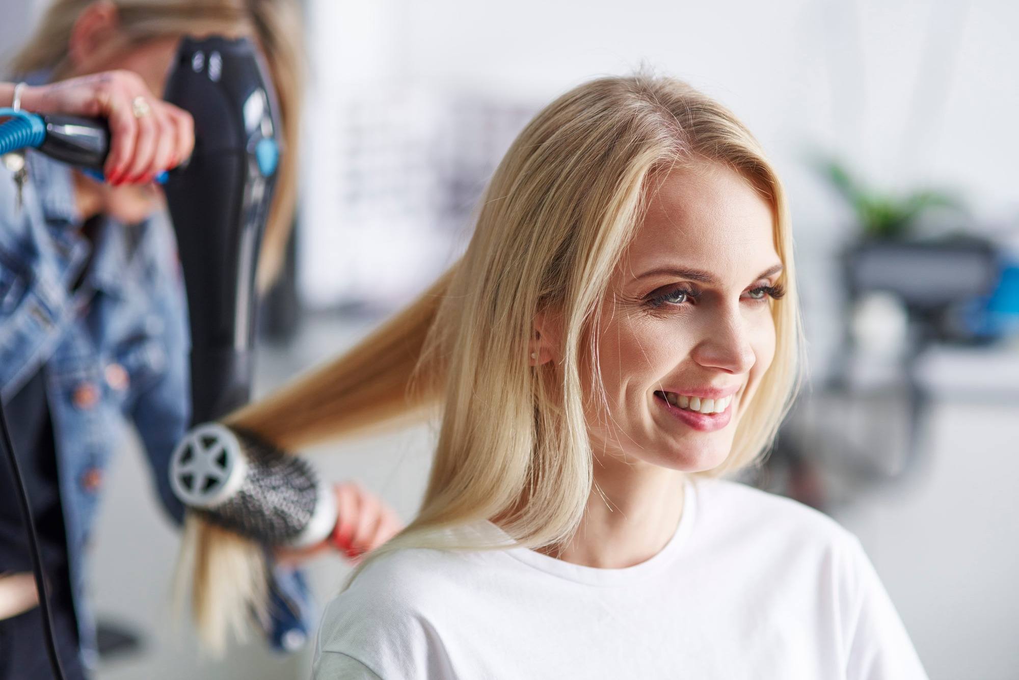 Une femme blonde chez le coiffeur se fait sécher les cheveux