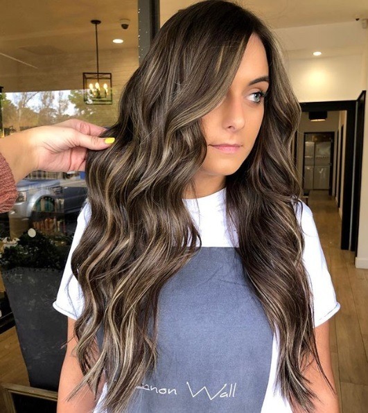 Femme aux longs cheveux bruns bouclés, balayage avec extensions
