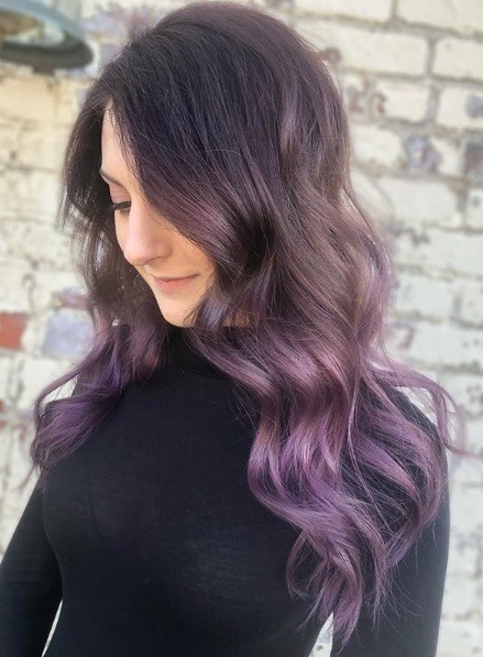 Femme avec de longs cheveux bouclés de balayage violet