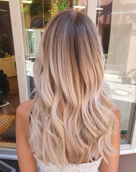 Femme aux longs cheveux ondulés et blonds clairs en balayage