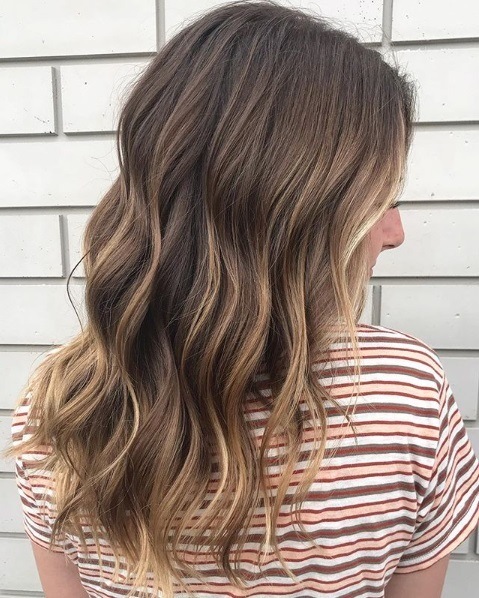 Femme avec des cheveux bruns ondulés de longueur moyenne en balayage