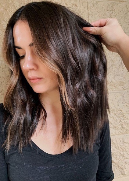 Femme à l'épaule ondulée subtilement brune balayage
