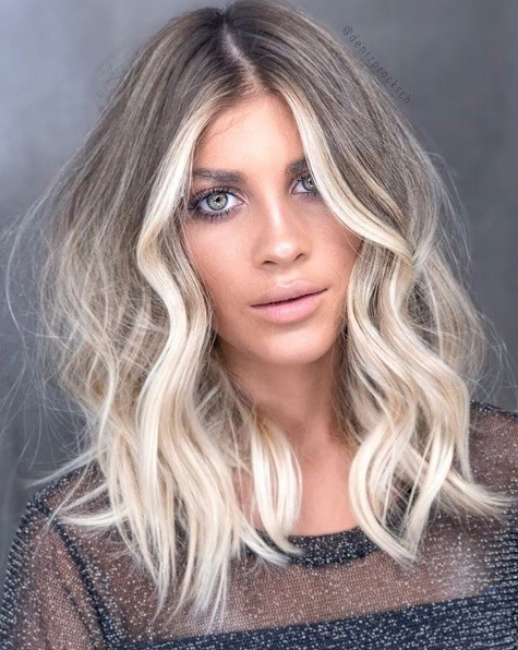 Femme avec un lob de balayage blond cendré et ondulé