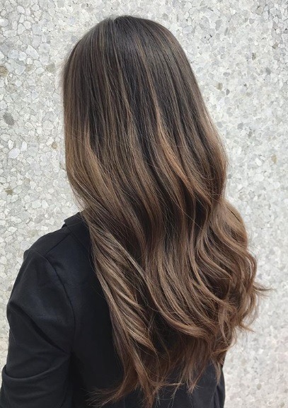 Femme aux longs cheveux bruns cendrés et ondulés en balayage