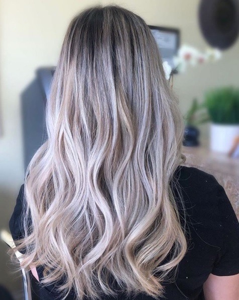 Femme avec de longs cheveux ondulés blonds cendrés en balayage