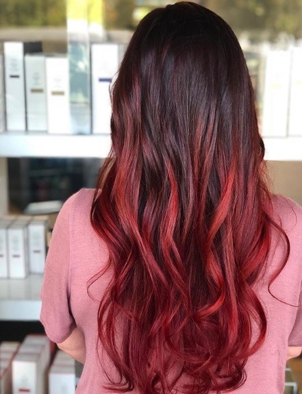 Femme avec un long balayage brun à rouge bouclé