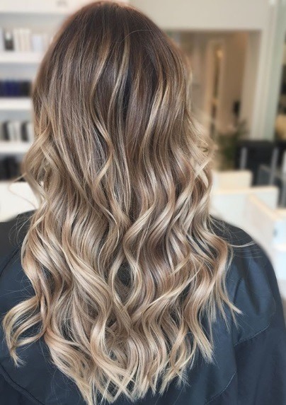 Femme avec de longs cheveux bouclés, blond foncé, en balayage