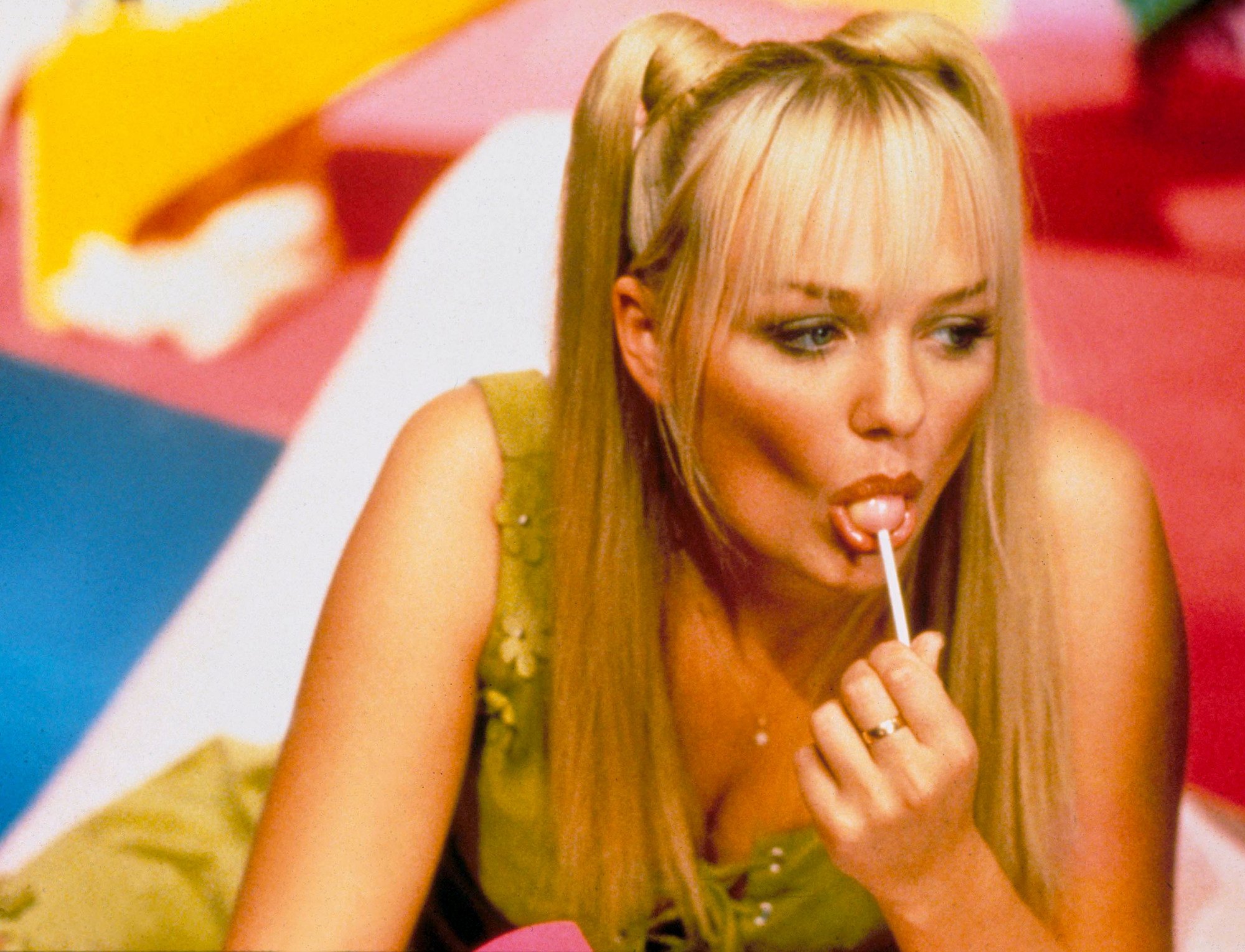 Coiffures des années 90 : Emma Bunton : longs cheveux blonds raides en nattes mangeant une sucette 