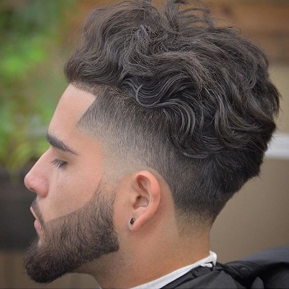 vue latérale d'un homme aux cheveux châtains moyens, dans un style mohawk bouclé avec une barbe fanée et façonnée