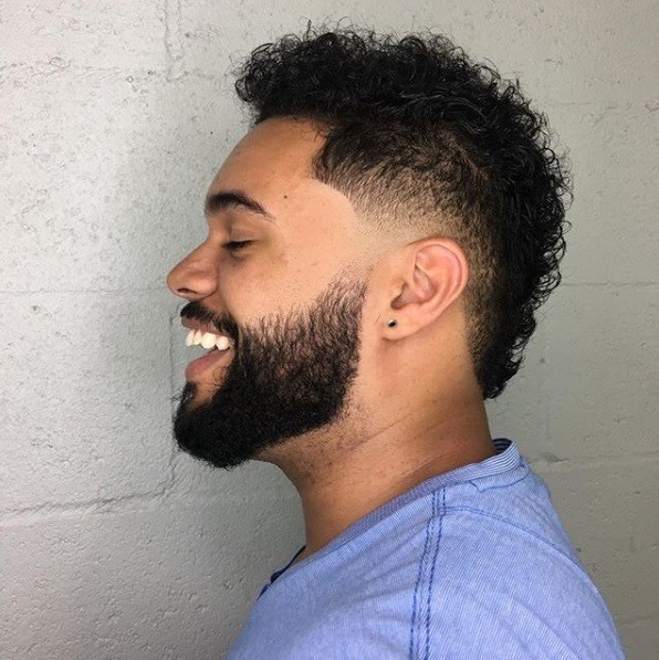 vue de côté d'un homme aux cheveux courts et bouclés coupés en fauxhawk avec une barbe