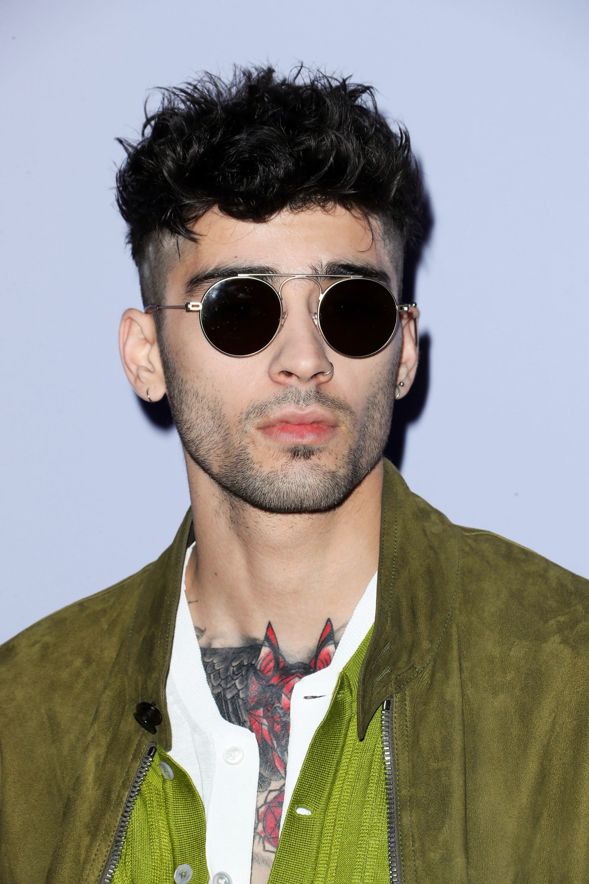 zayn malik avec des cheveux ondulés, hauts et serrés, portant des lunettes de soleil rondes et une veste verte