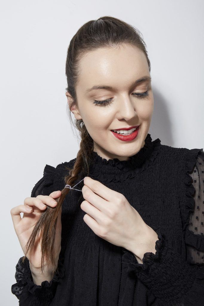 Comment tresser ses propres cheveux en France Fille brune qui noue sa tresse avec une cravate