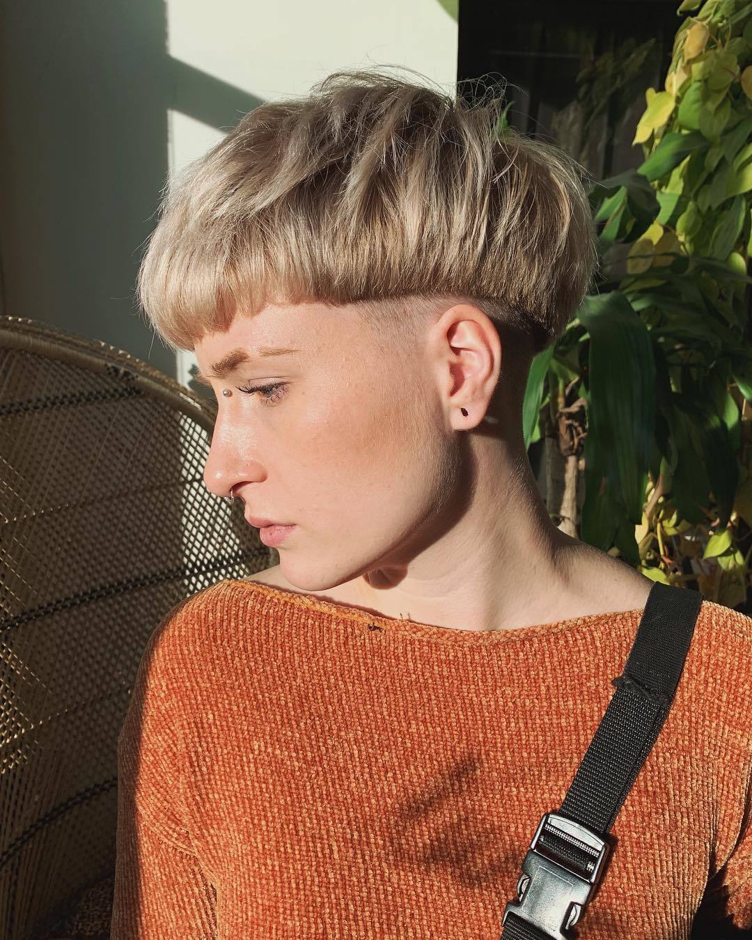 Femme avec une coupe de cheveux blonde en bol et une coupe de cheveux rasée en dessous.