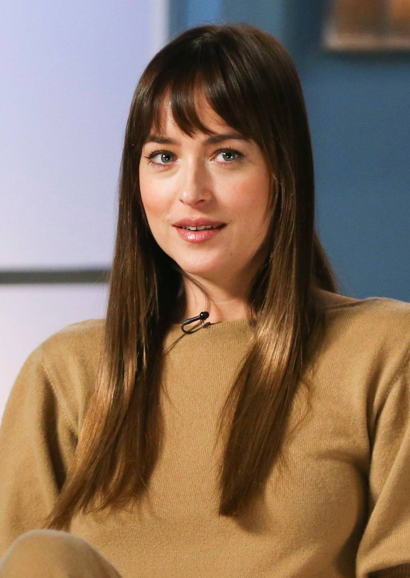 Coupes de cheveux pour cheveux fins et raides : Gros plan de Dakota Johnson avec de longs cheveux bruns raides avec une frange.