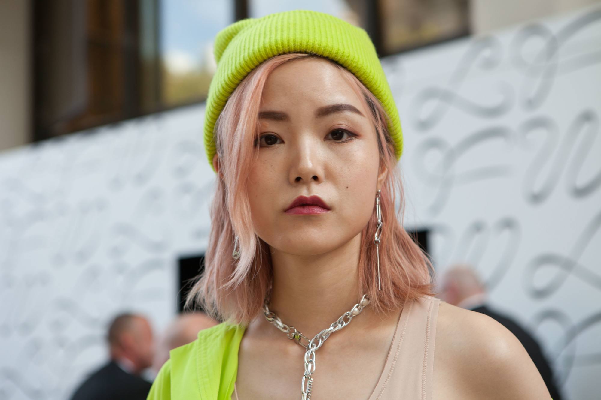 Femme aux cheveux asiatiques roses, longs d'épaule, avec un bonnet jaune fluo.