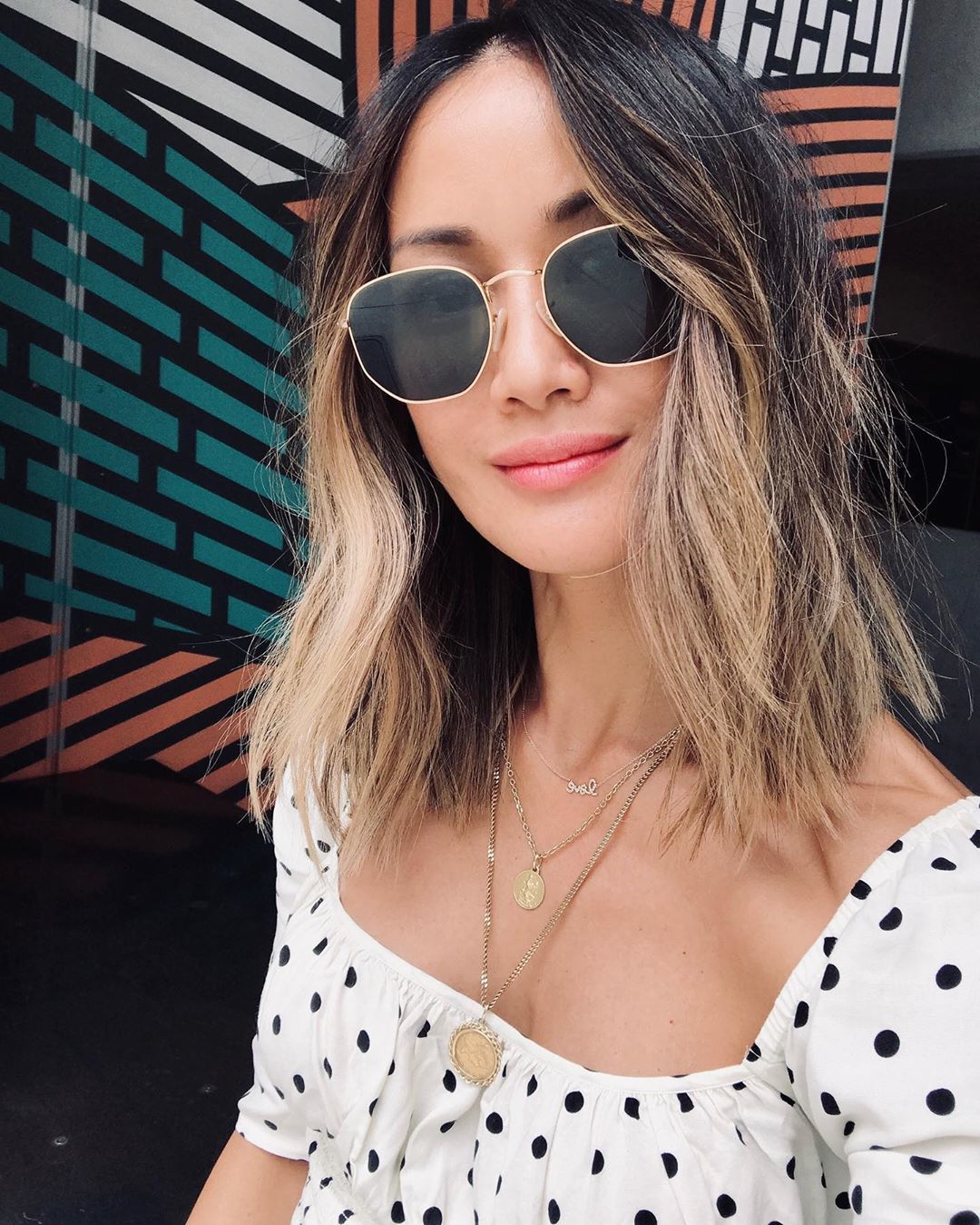 Femme asiatique avec une coupe de cheveux blonde ombrée, mi-longue et dégradée.